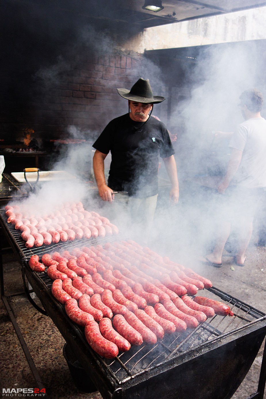 grillmaster cooking chorizo for choripan in san telmo market buenos aires argentina