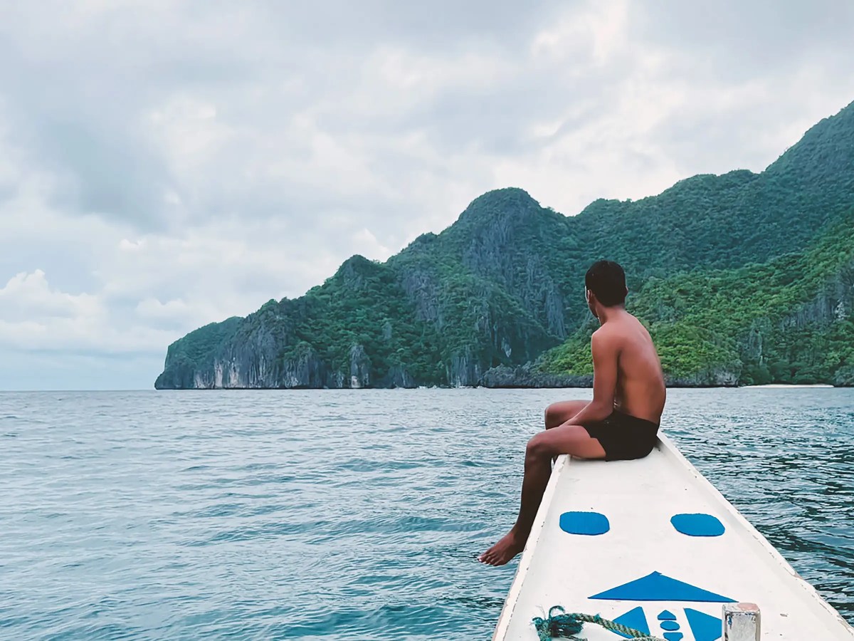Filipino guide sitting on bow of boat during tour in El Nido