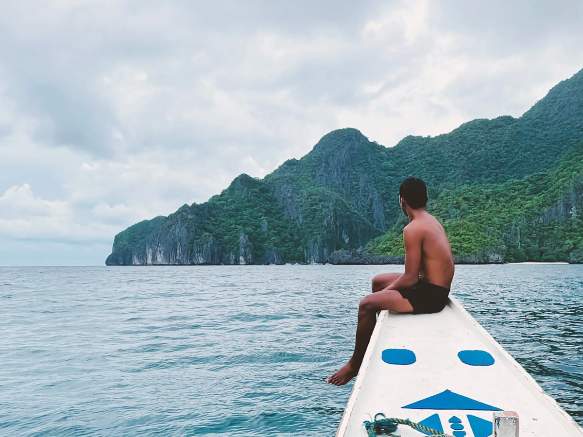 Filipino guide sitting on bow of boat during tour in El Nido