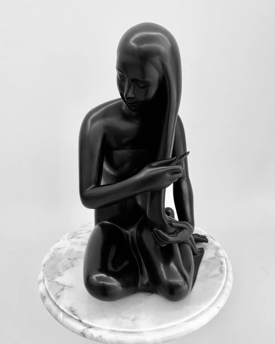 black and white photo of a sculpture of a woman combing her hair by Suthep Nualnuch