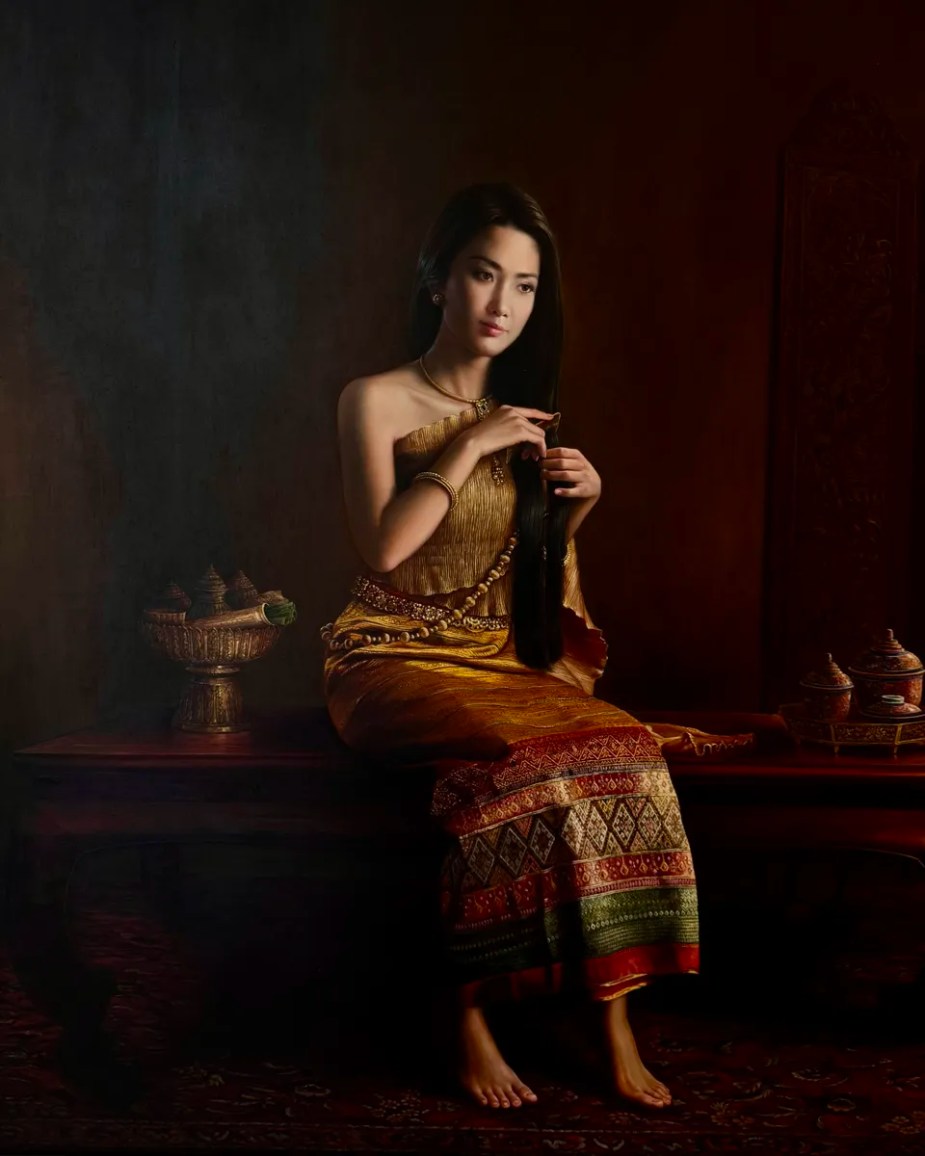 a painting by Suporn Printhrakul called Lady of the Fragrant Hair of a beautiful thai woman in a traditional gold and red dress combing her long hair