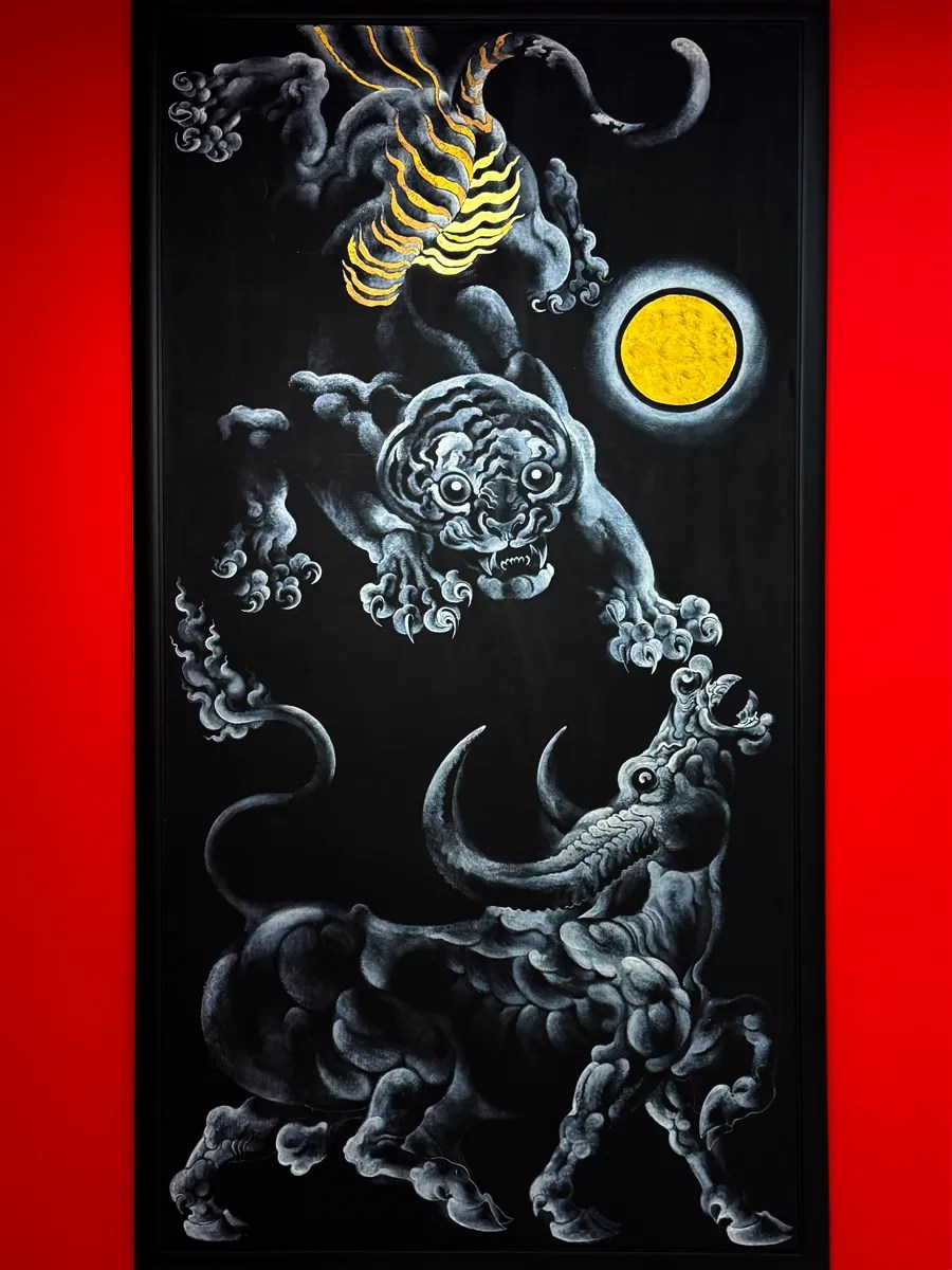 a contemporary thai painting by Thawan Duchanee in black and gold that depict a tiger and ox in front of a golden moon